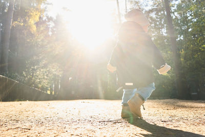 Baby boy walking on footpath against trees in sunny day