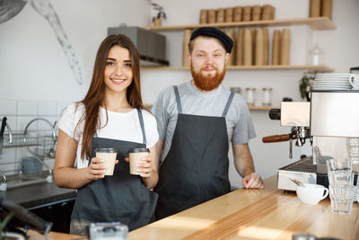 Portrait of smiling young woman using mobile phone while sitting in cafe