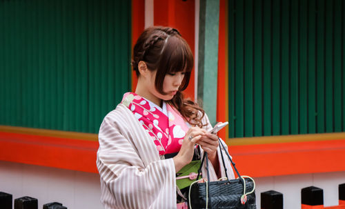 Young woman standing against red wall