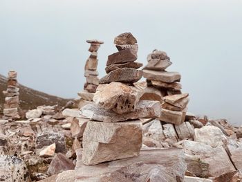 Stack of stones on rock against sky