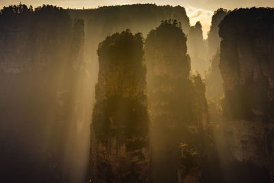 Breathtaking top mountain scenery with spectacular sunbeam on foggy day