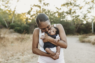 Portrait of young mother holdiing infant daughter in backlt field