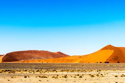 Scenic view of desert against clear blue sky