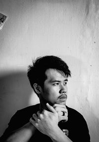 Portrait of young man smoking cigarette against wall