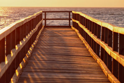 Empty wooden pier on sea against sky