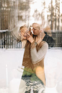 Portrait of a man and a woman in love hugging and kissing taken through the window of the house