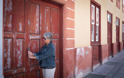 Side view of woman standing against building