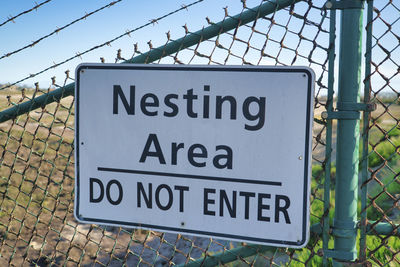 Close-up of warning sign on chainlink fence