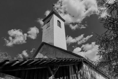 Low angle view of cross by building against sky