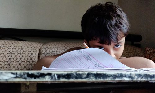 Portrait of boy writing in book at home