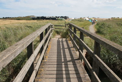 Footbridge over footpath amidst field against sky