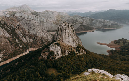 Scenic view of a lake, rocks and mountains against sky