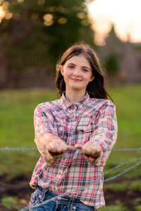 Portrait of young woman gripping barbed wire fence