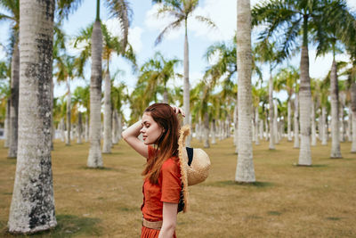 Portrait of young woman standing against trees