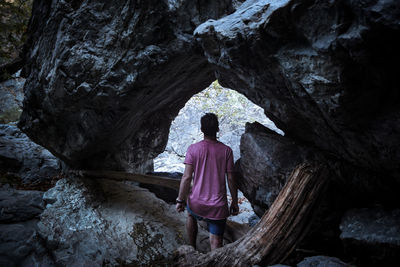 Rear view of man standing by rock formations