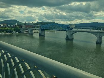 Bridge over river against cloudy sky