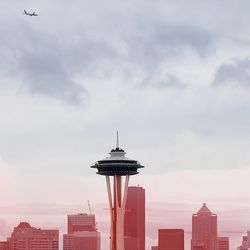 Low angle view of communications tower against cloudy sky