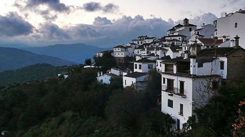 Buildings in town against cloudy sky