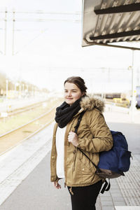 Young woman with backpack waiting at train station