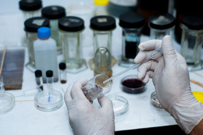 Cropped hand of scientist holding medical sample in container at laboratory