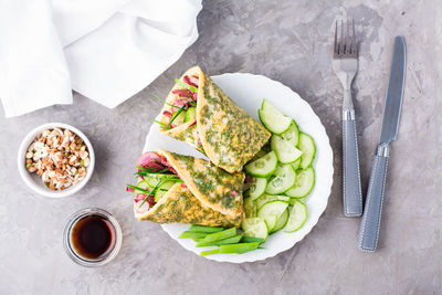 Egg rolls filled with pastrami, vegetables and green onions on a plate, sprouted grains 