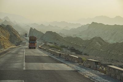 Truck moving on road against mountains during foggy weather