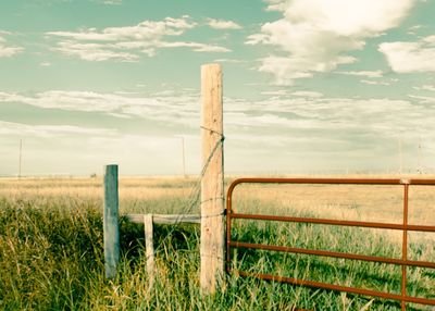 Wooden fence on field against sky