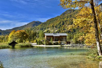 House by lake against sky