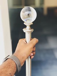 Close-up of hand holding metal rod with crystal ball on top