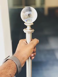 Close-up of hand holding clock against blurred background