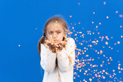 Portrait of boy eating food against blue background