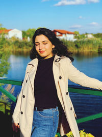 Young woman standing against lake