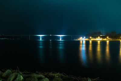 Illuminated bridge over water at night