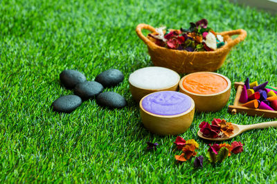 High angle view of beauty products with colorful petals and pebbles on grassy field