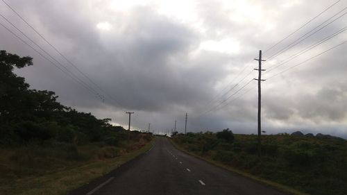 Electricity pylon by road against sky