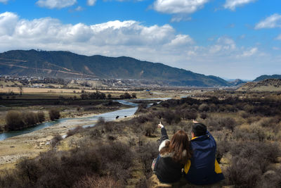 Rear view of people standing on mountain against sky