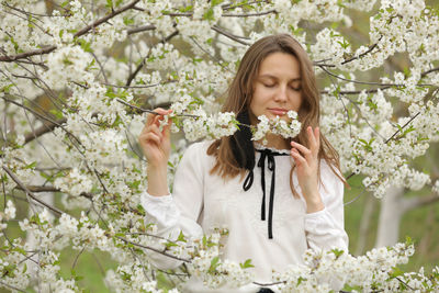 Woman took off her mask to inhale the smell of flowers. girl touches the blossoming cherry tree 