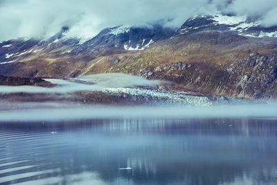 Scenic view of lake by snowcapped mountains against sky