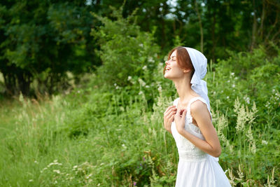 Young woman standing against plants