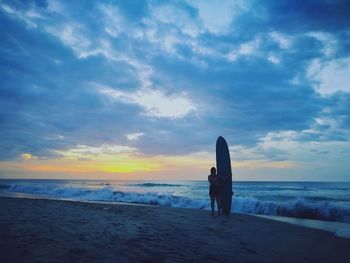 Silhouette woman standing on beach against sky during sunset