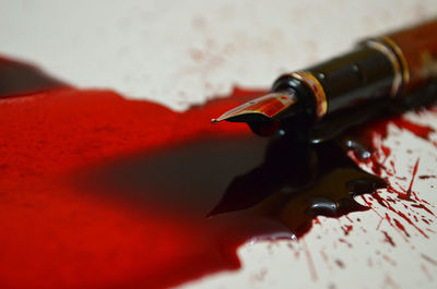 Close-up of splattered red ink and pen on table