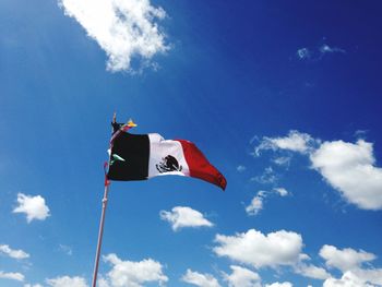 Low angle view of mexican flag against cloudy sky