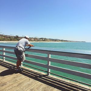 Rear view of man against sea against clear sky