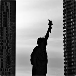 Silhouette man standing against modern buildings