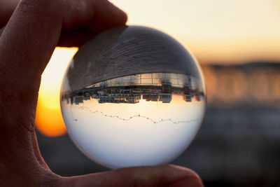 Cropped hand holding crystal ball with reflection