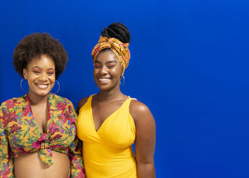 Portrait of two women against blue background. one of them is pregnant. 