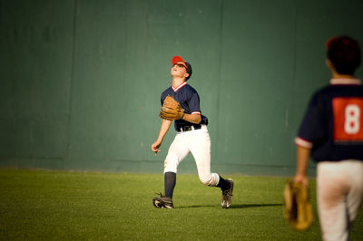 Young baseball player in sunglasses looking up at a fly ball