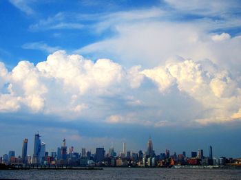 Sea by modern buildings against sky in city