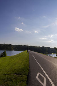 Road by grass against sky