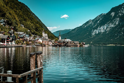 Scenic view of lake by houses and mountains against sky